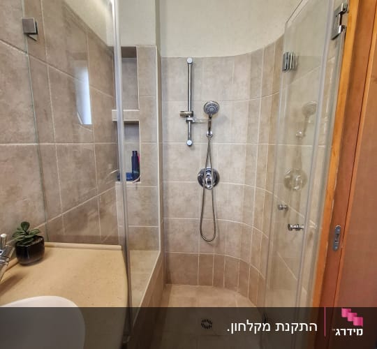 מקלחת עם דלת זכוכית וראש מקלחת